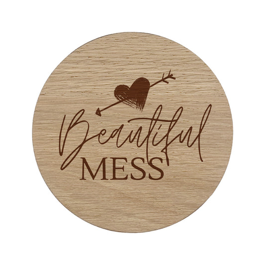 Round wooden coaster with 'Beautiful Mess' text and heart design on a white background
