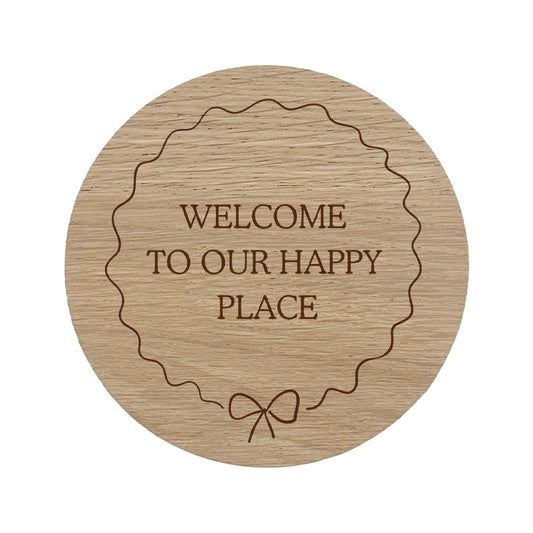 Wooden coaster with 'Welcome to our happy place' text and bow border.