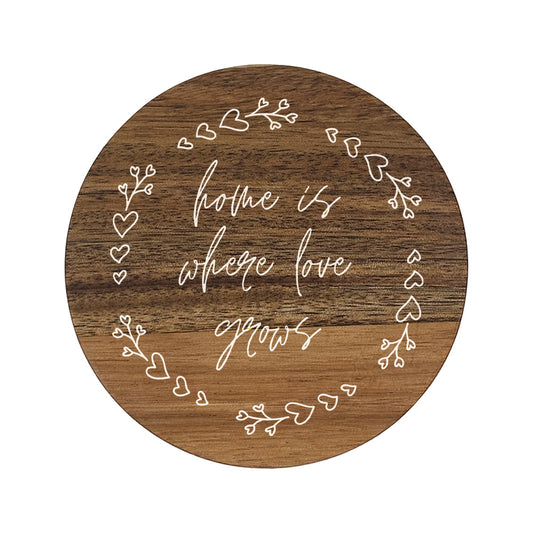 Round wooden coaster with decorative text 'home is where love grows' and heart designs on a white background