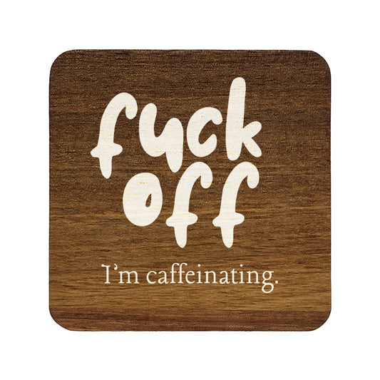 Square wooden coaster with white text 'f*ck off I'm caffeinating.' on a white background
