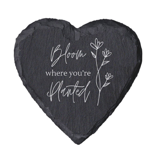 Heart-shaped slate with 'Bloom where you're planted' text and floral design on a white background