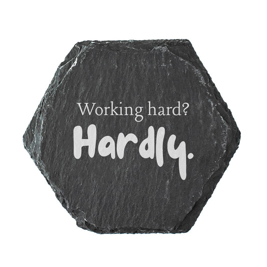 Hexagonal black slate coaster with 'Working hard? Hardly.' text on a white background