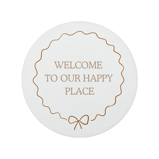 Round ceramic coaster featuring the quote "Welcome to our happy place" in neutral toned lettering with a cute bow border.
