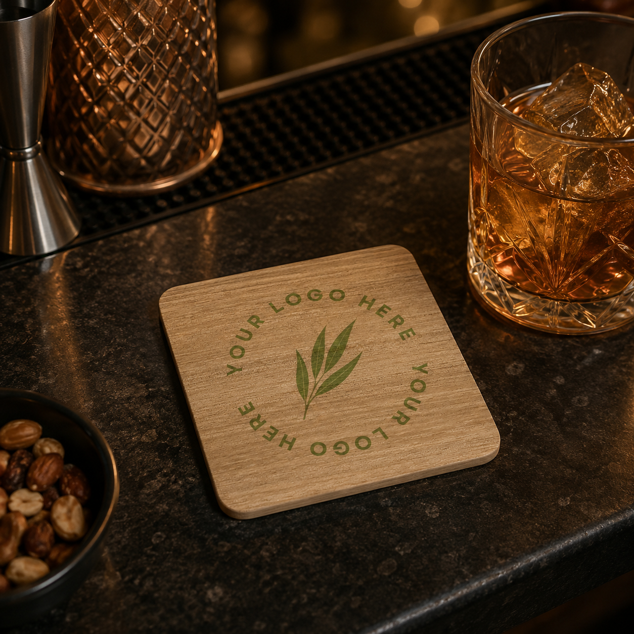 A square wooden bar coaster with a custom personalised logo, displayed on a dark bar counter next to a glass of amber drink.