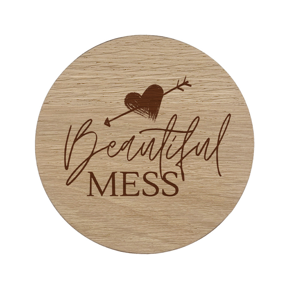 Round wooden coaster with 'Beautiful Mess' text and heart design on a white background