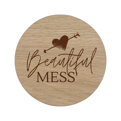 Round wooden coaster with 'Beautiful Mess' text and heart design on a white background