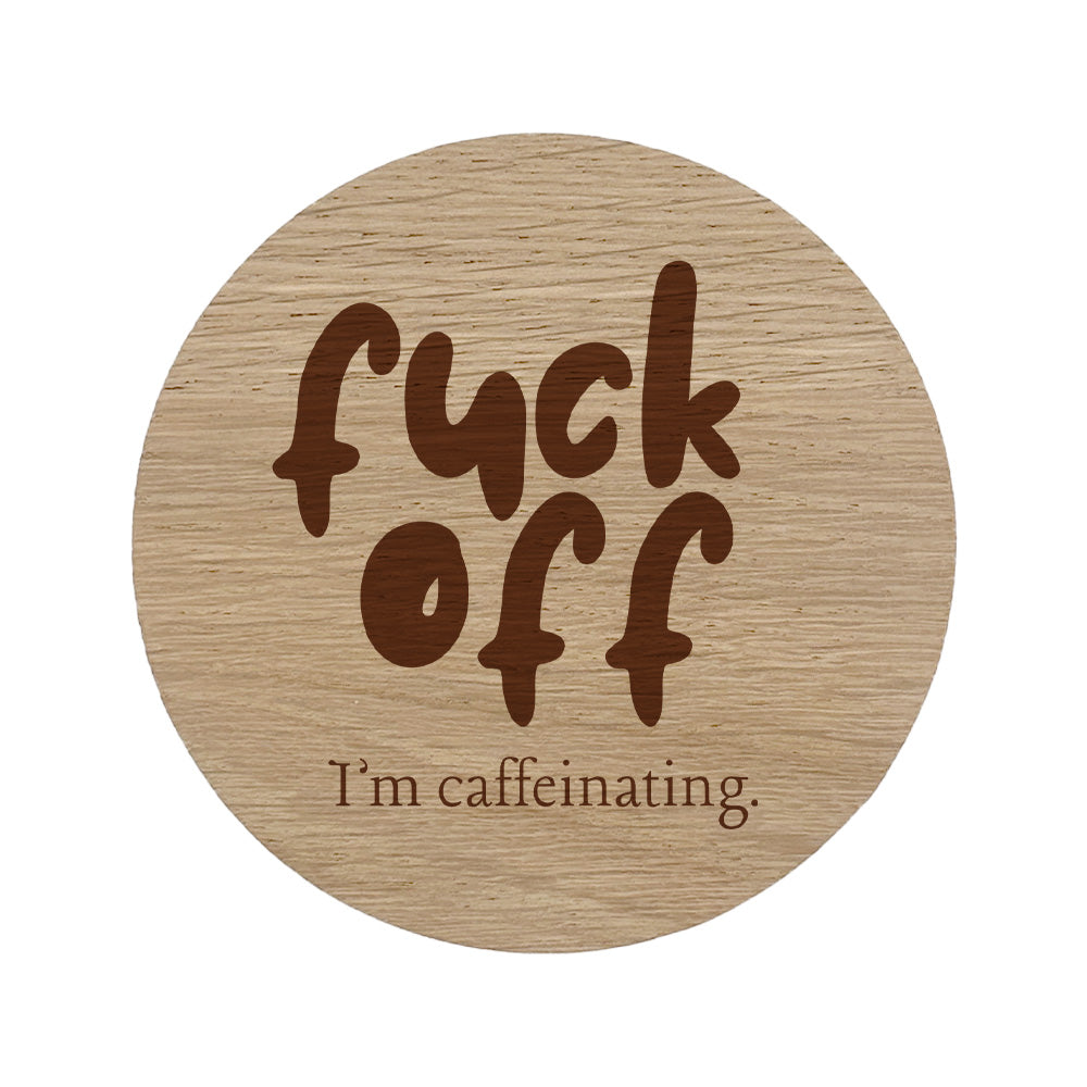 Wooden coaster with 'fuck off I'm caffeinating' text.