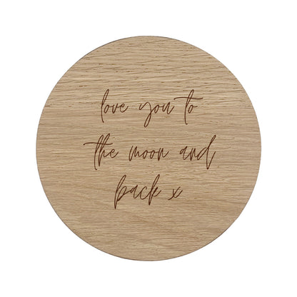 Round wooded coaster with quote "love you to the moon and back x" in handwriting style lettering.