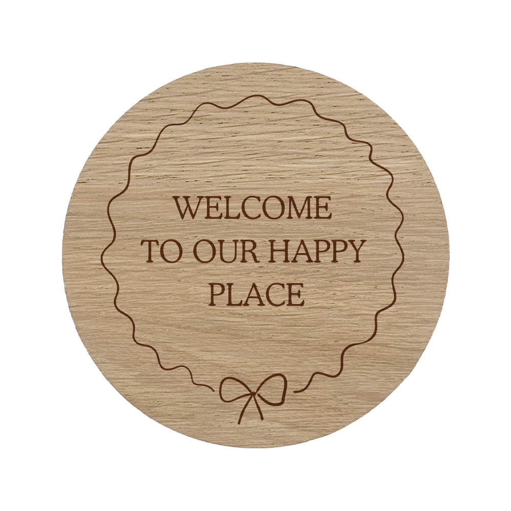 Wooden coaster with 'Welcome to our happy place' text and bow border.