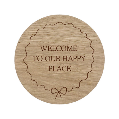 Wooden coaster with 'Welcome to our happy place' text and bow border.