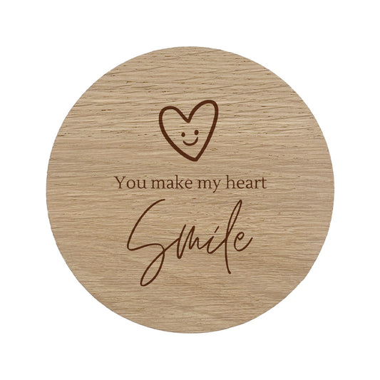 Round wooden coaster with a heart and "You make my heart smile" text design on a white background
