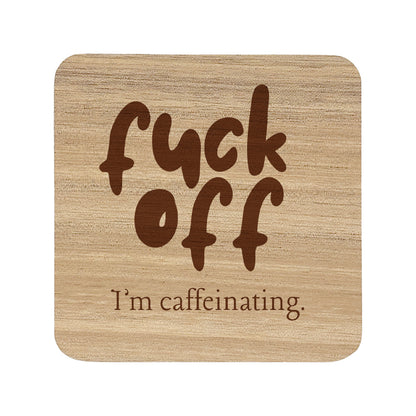 Wooden coaster with text 'fuck off I'm caffeinating' on a white background
