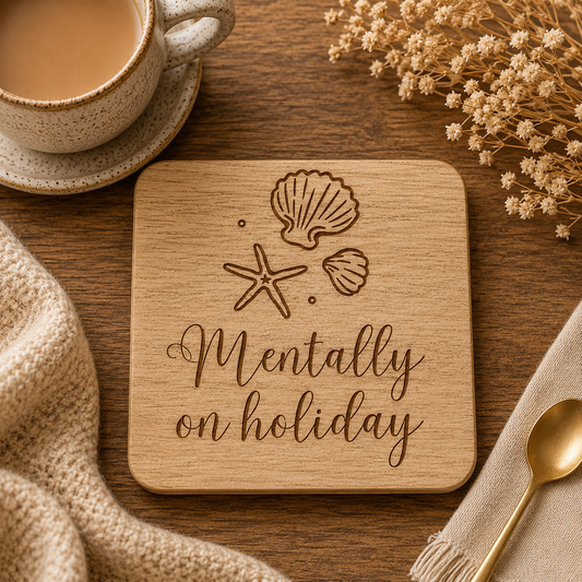 Wooden coaster with 'Mentally on holiday' text and shell designs on a wooden table with a cup of coffee and dried flowers.