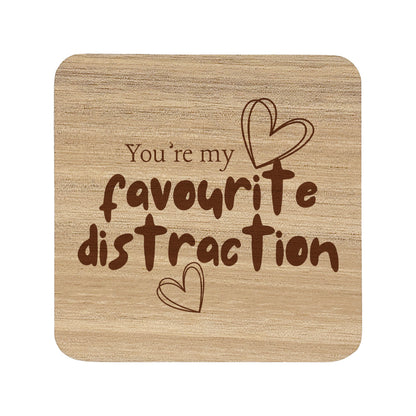 Square wooden coaster with the quote 'You're my favourite distraction' and heart illustrations.