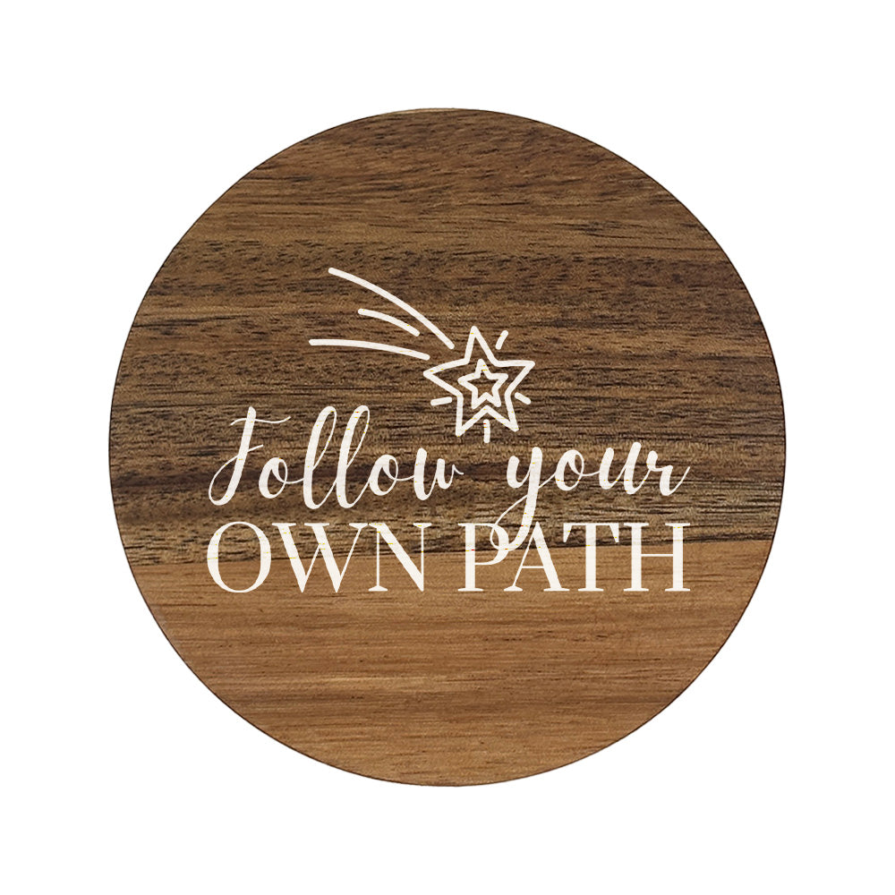 Round wooden coaster with 'follow your own path' white text and shooting star illustration.