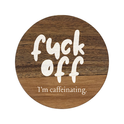Square wooden coaster featuring the humorous quote "Fuck off I'm caffeinating" in crisp white lettering.