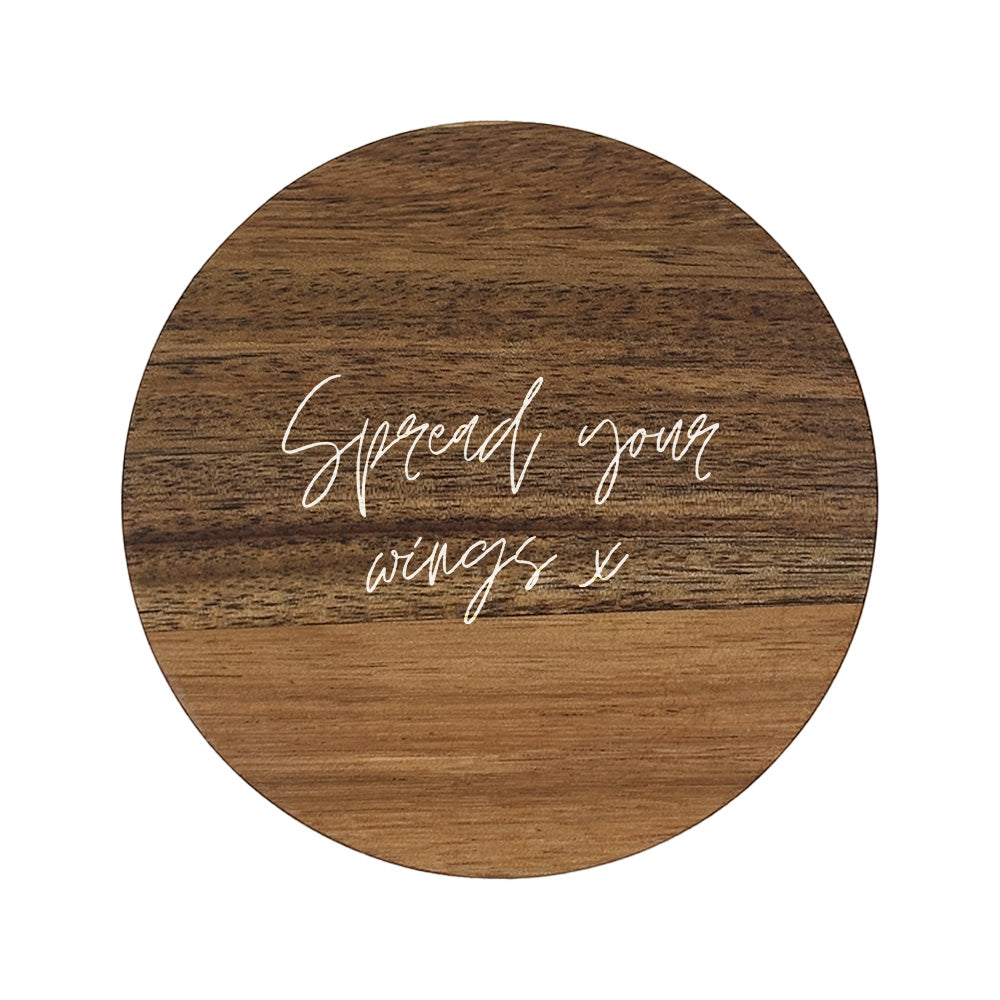 Round wooden coaster with 'Spread your wings' text 