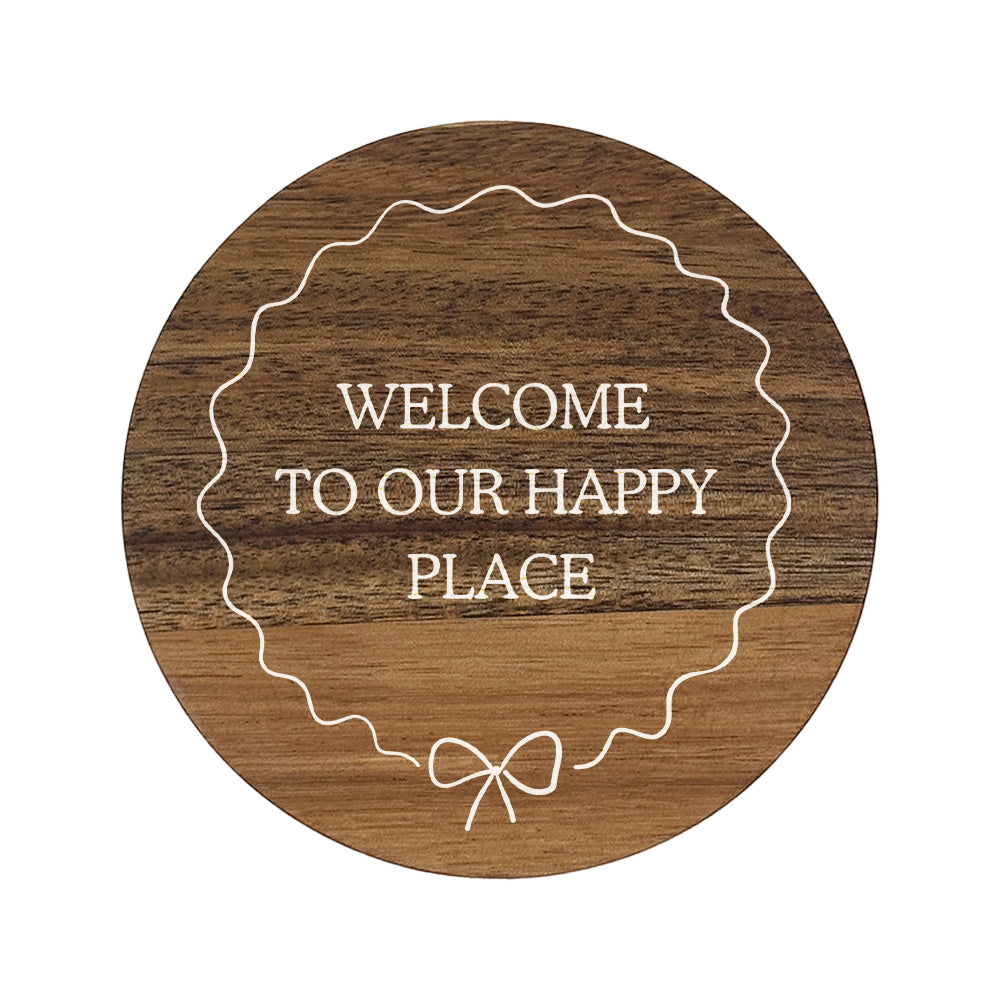 Round wooden coaster with 'Welcome to our happy place' text 