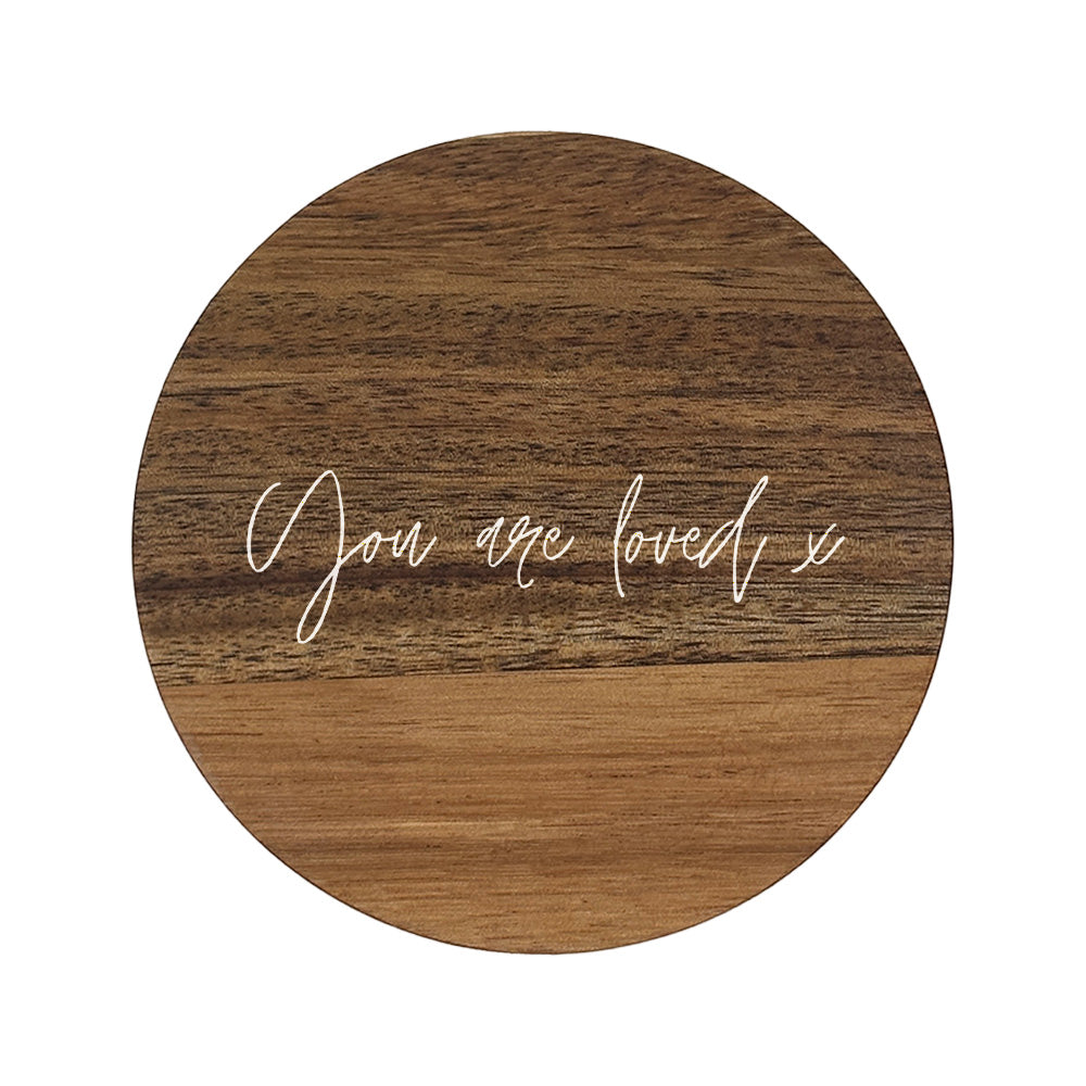 Round wooden coaster with 'You are loved x' text on a white background