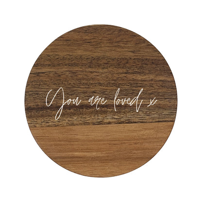 Round wooden coaster with 'You are loved x' text on a white background
