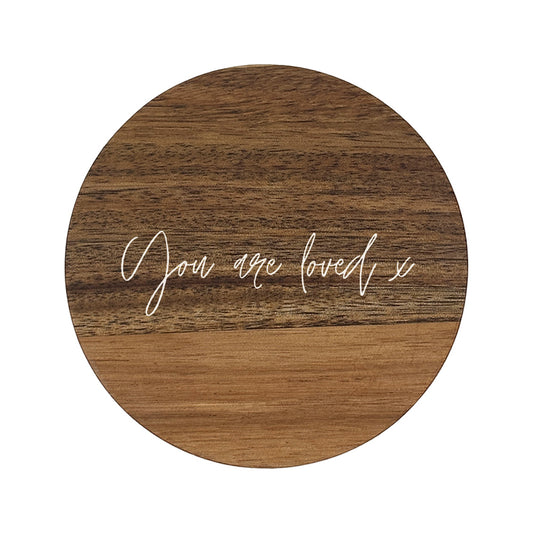 Round wooden coaster with 'You are loved x' text on a white background