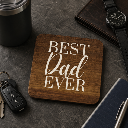 Square wooden coaster with 'Best Dad Ever' text on a dark surface with keys, watch and accessories.