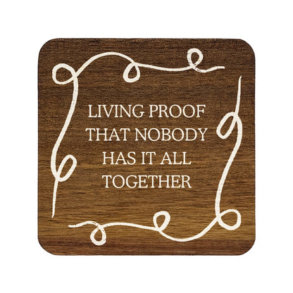 Square wooden coaster with quote 'Living proof that nobody has it all together' in white lettering.