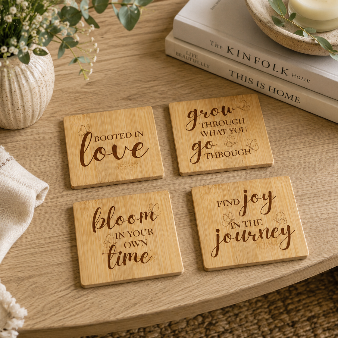 A set of 4 bamboo wood coasters on a wooden coffee table, decorated with inspirational quotes about growth and transformation.
