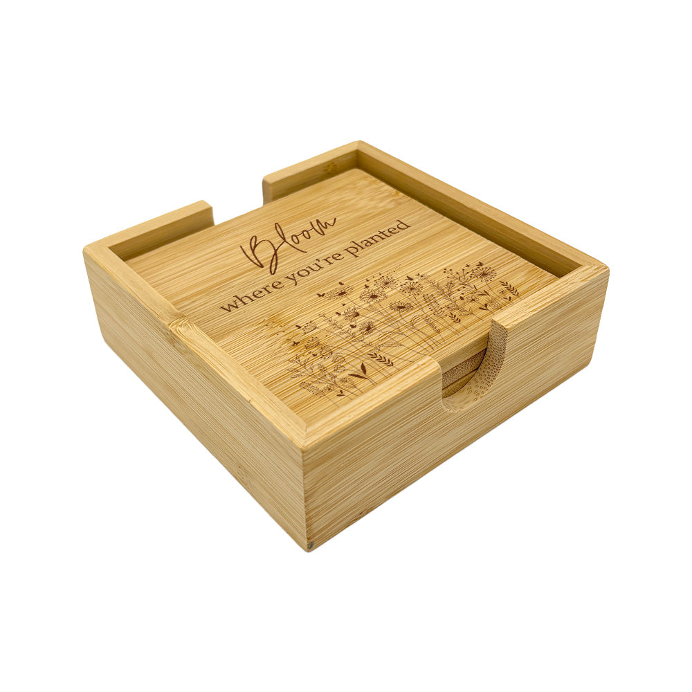 A set of 4 bamboo wood coasters decorated with inspirational quotes and wildflower illustrations. The coasters are stored in a matching bamboo box.