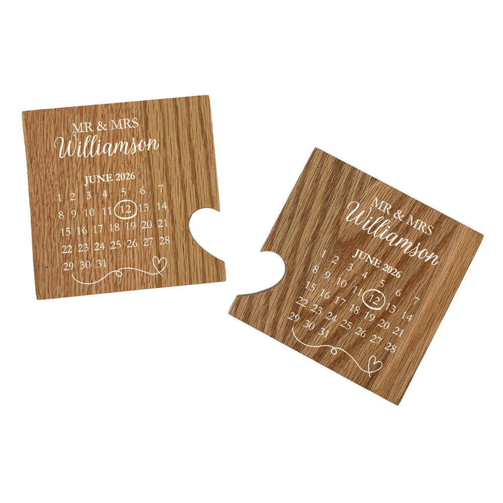 A set of 2 oak coasters personalised with a wedding or anniversary calendar and the couple's name in white text. When placed together a cut-out on each of the coasters forms a heart.