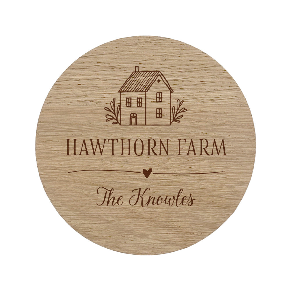 Round wooden coaster with personalised house illustration and house and family name on a white background