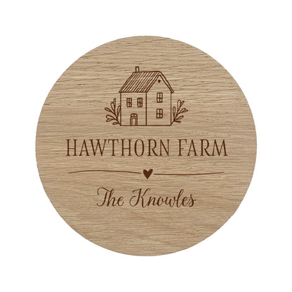 Round wooden coaster with personalised house illustration and house and family name on a white background