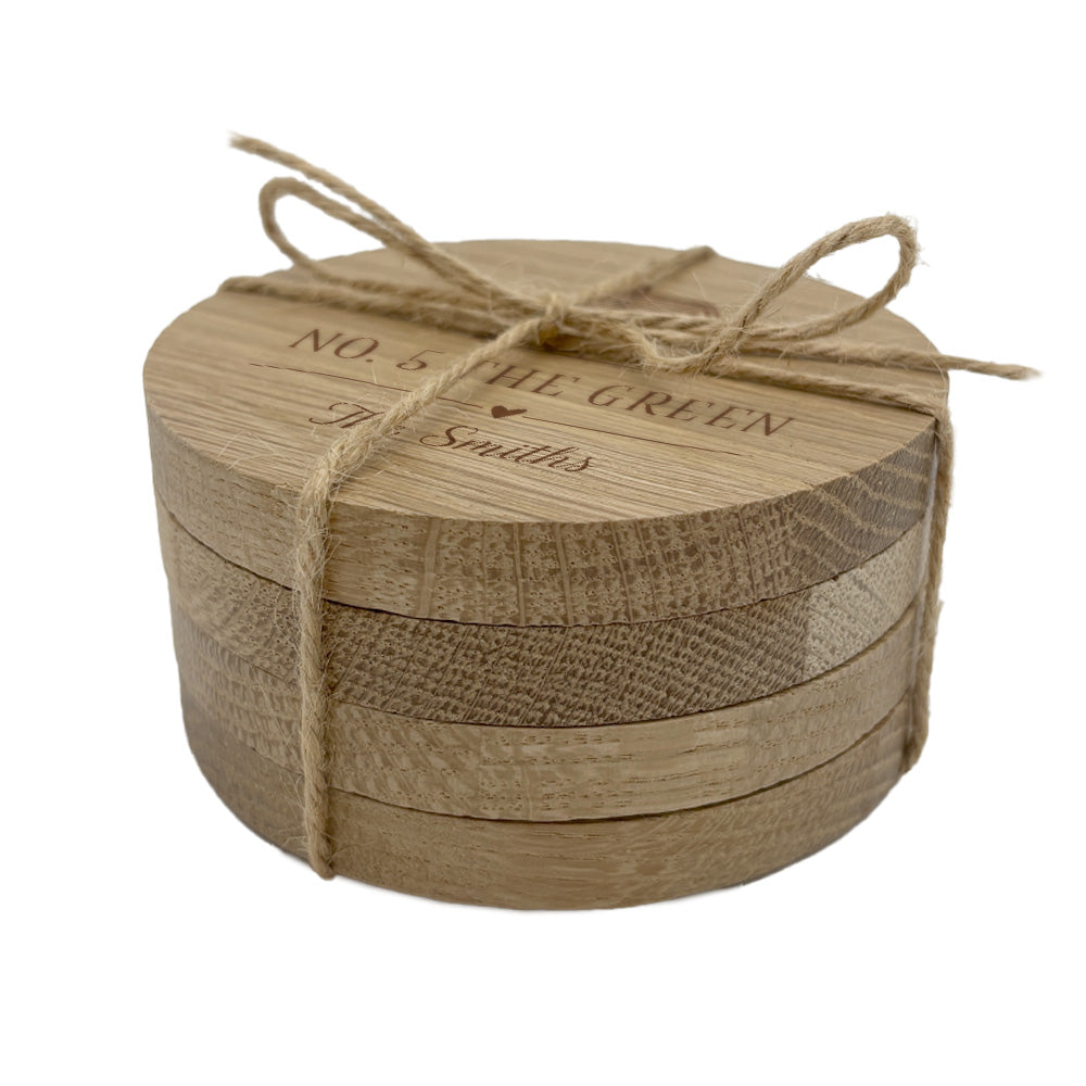 Round wooden set of personalised housewarming coasters with jute string on a white background