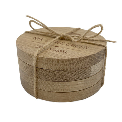 Round wooden set of personalised housewarming coasters with jute string on a white background
