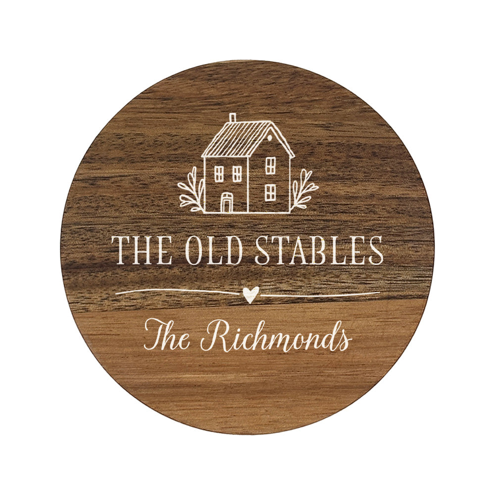 Wooden round coaster with house illustration and personalised house name and family name in white text.