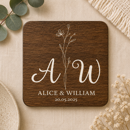 Square wooden coaster with personalised initials 'AW' and names 'Alice & William' on a beige fabric background.