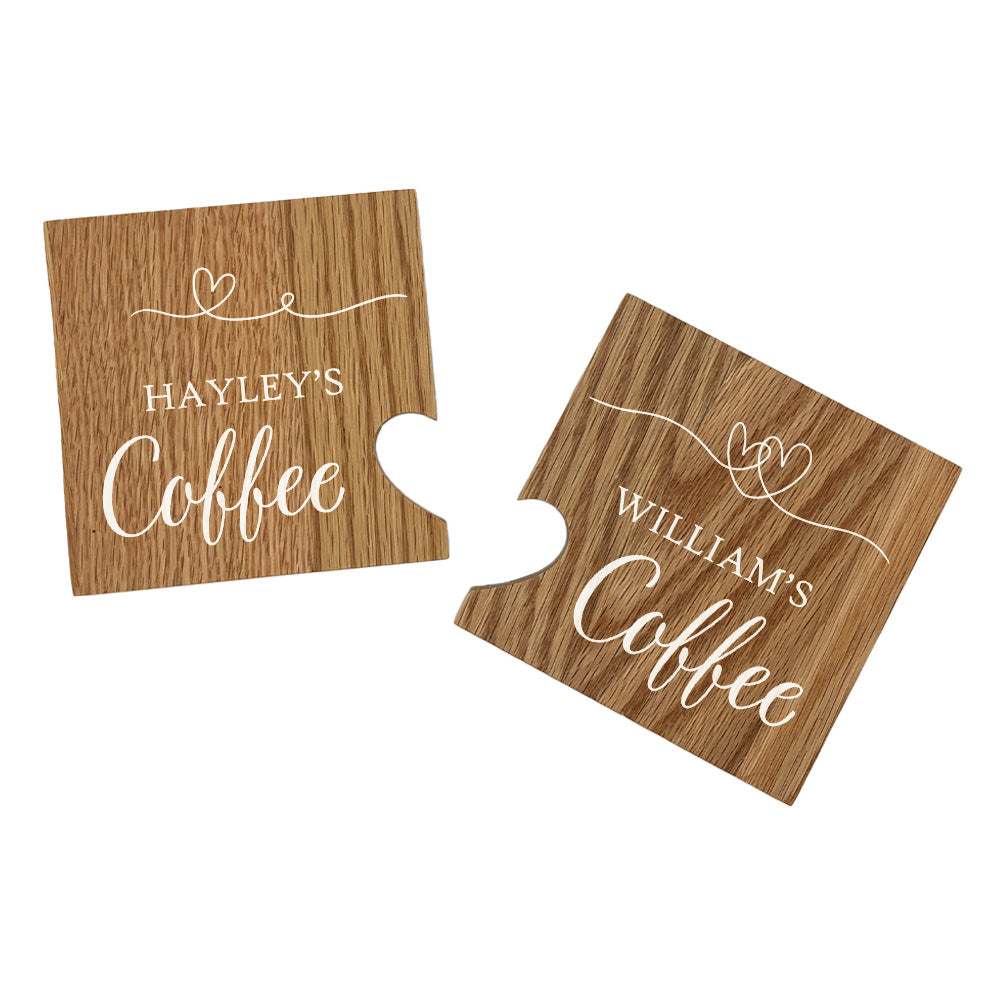 A set of 2 personalised oak coasters with a cut out heart created when the coasters are placed together. The personalised text has a name on each coaster and their favourite hot drink e.g. 'Ryan's Tea'.