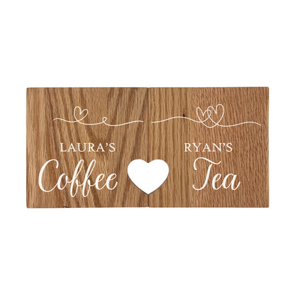A set of 2 personalised oak coasters with a cut out heart created when the coasters are placed together. The personalised text has a name on each coaster and their favourite hot drink e.g. 'Ryan's Tea'.