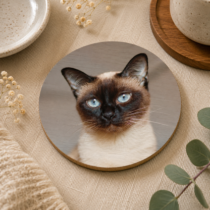 Round wooden coaster personalised with a photo of a cat's face on a beige surface with decorative elements