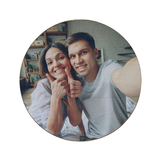 A round wooden coaster personalised with a photo of a couple smiling.
