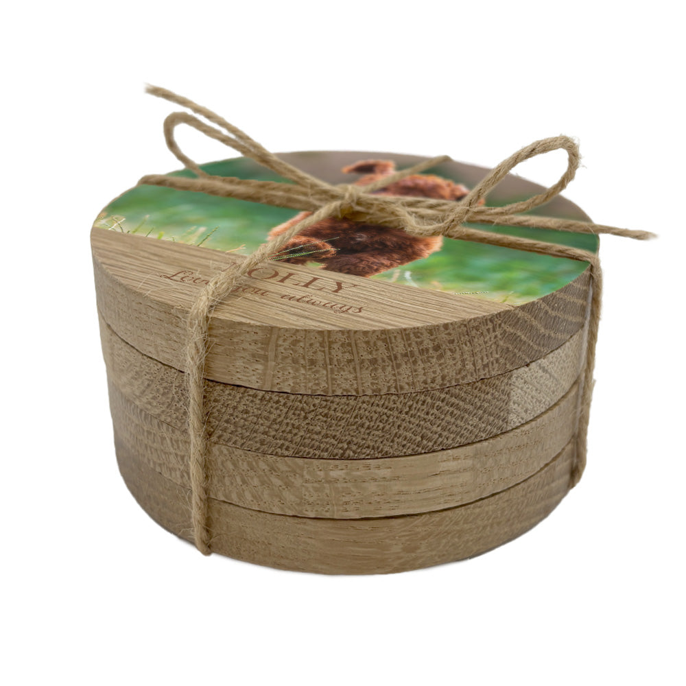 Stack of round wooden coasters with a natural wood finish and personalised photo and text, tied with twine on a white background.