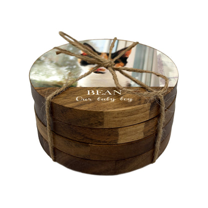 Stack of wooden coasters personalised with a photo and custom text, tied with twine on a white background.
