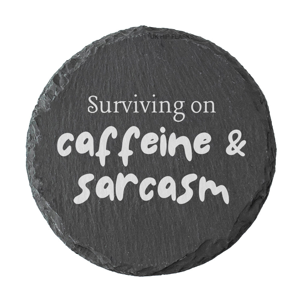Round coaster with the quote "surviving on caffeine and sarcasm" in white text.