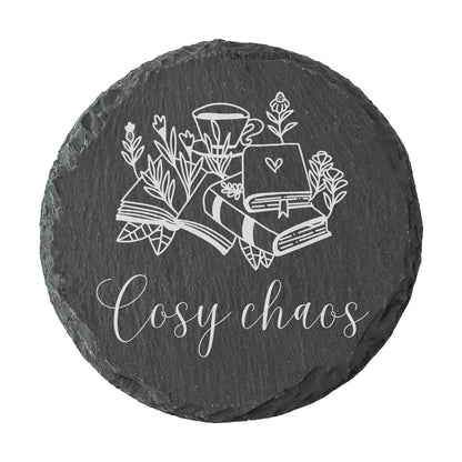 Round slate coaster with the quote "Cosy chaos" in white text.