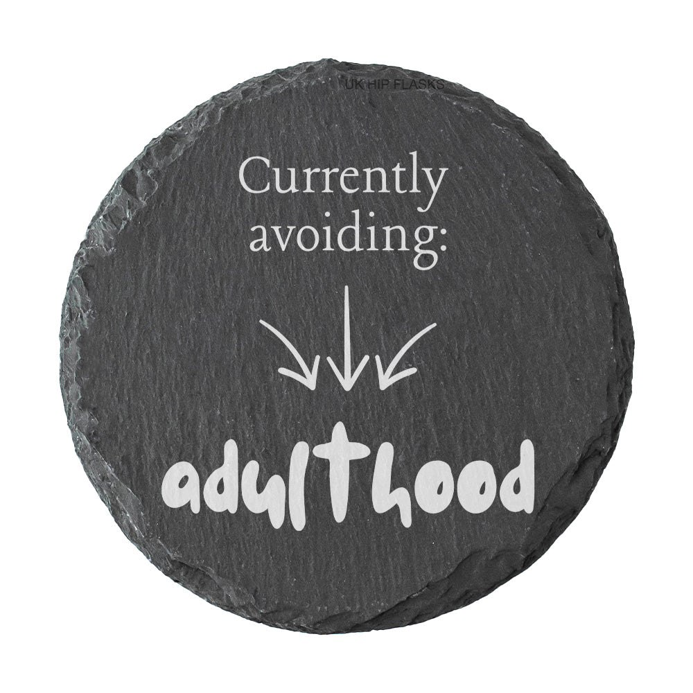 Round slate coaster with humorous text 'Currently avoiding: adulthood' on a white background