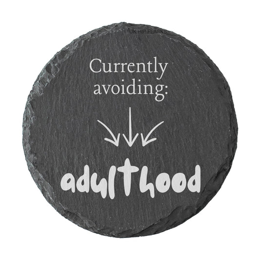 Round slate coaster with humorous text 'Currently avoiding: adulthood' on a white background