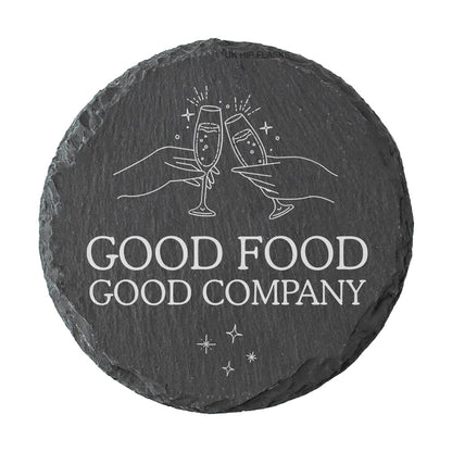 A round slate coaster with the quote "Good food good company" in white text.