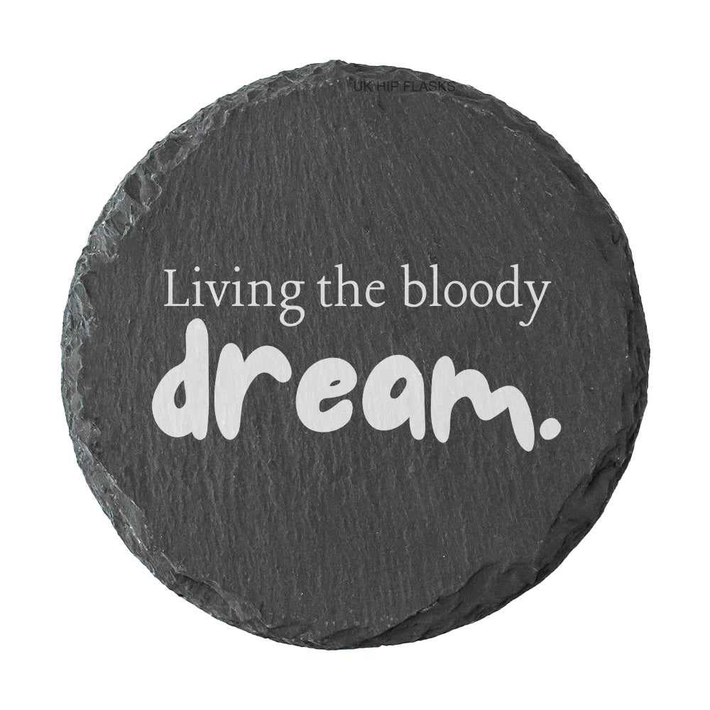 Round slate coaster with 'Living the bloody dream.' text on a white background