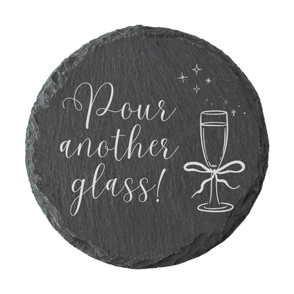 Round slate coaster with 'Pour another glass!' text and champagne glass illustration on a white background