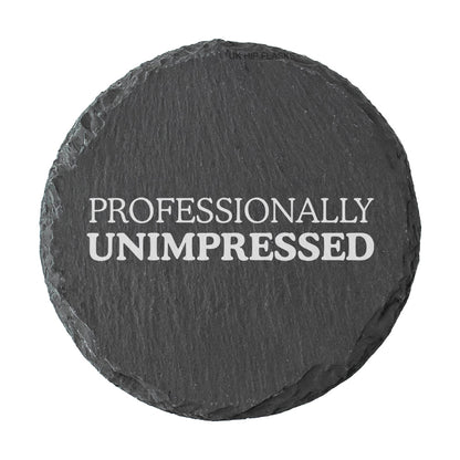 Round slate coaster with 'PROFESSIONALLY UNIMPRESSED' text on a white background